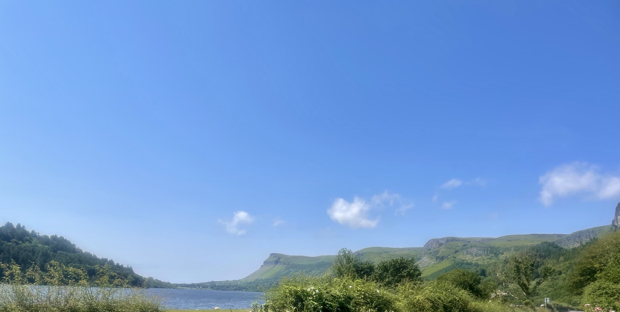 Irish lake and green mountains beneath a wide blue sky, photographed by Declan Loughlin